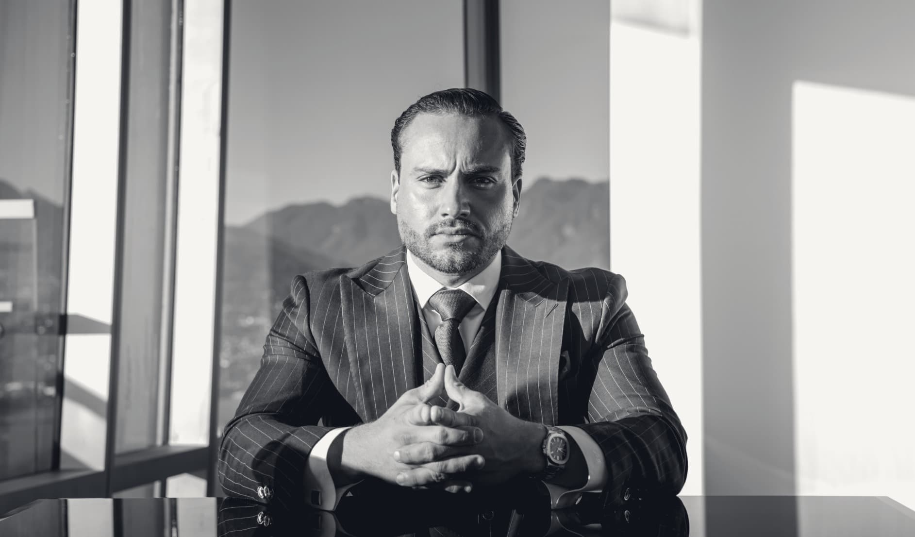 Louis Garoz-Ferguson seated at the boardroom table, the North Shore mountains through the glass behind him.