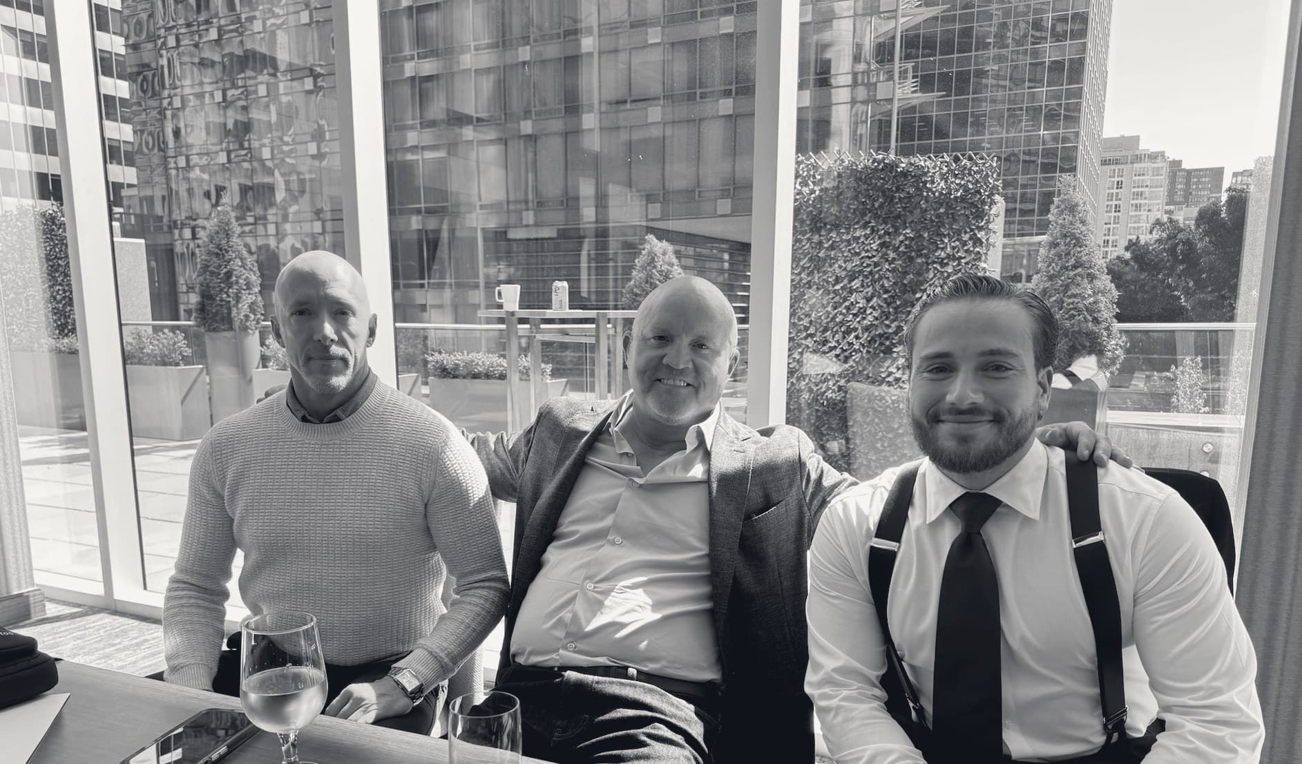 Three Kadenwood principals seated together, the Vancouver financial district through the glass behind them.