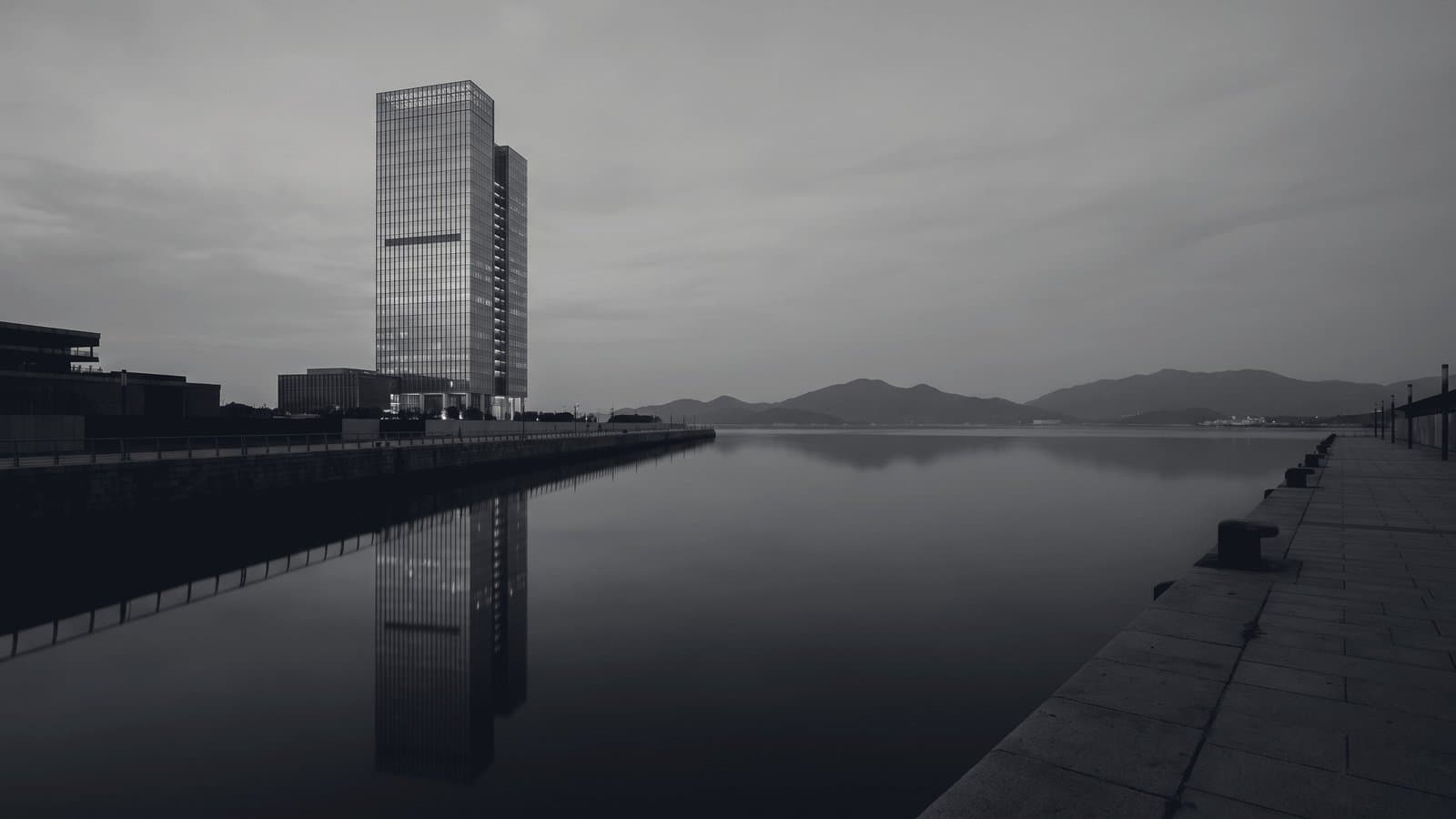 A single tower on a harbor front under flat grey light.
