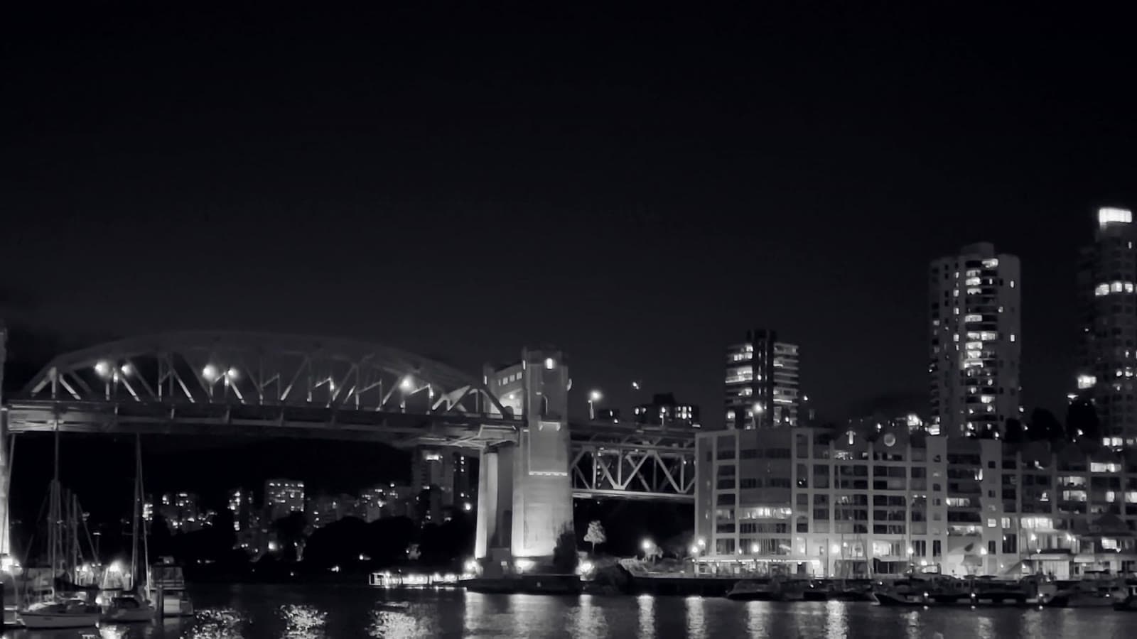 The Burrard Bridge at night, spanning dark water between two shores.