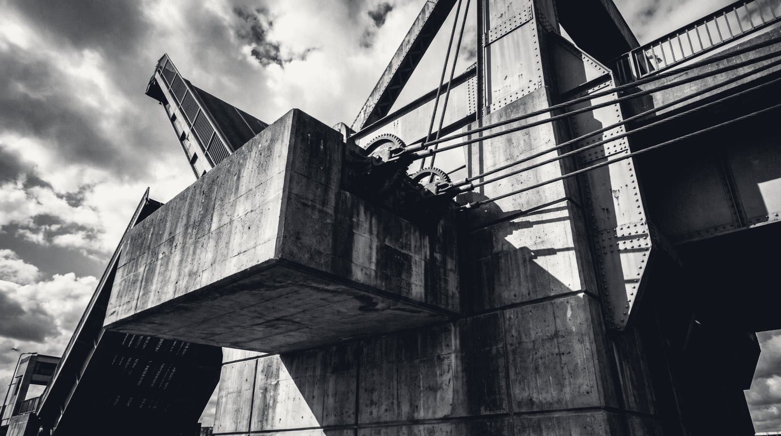 The concrete counterweight of a lift bridge, cables under tension running to the raised span.