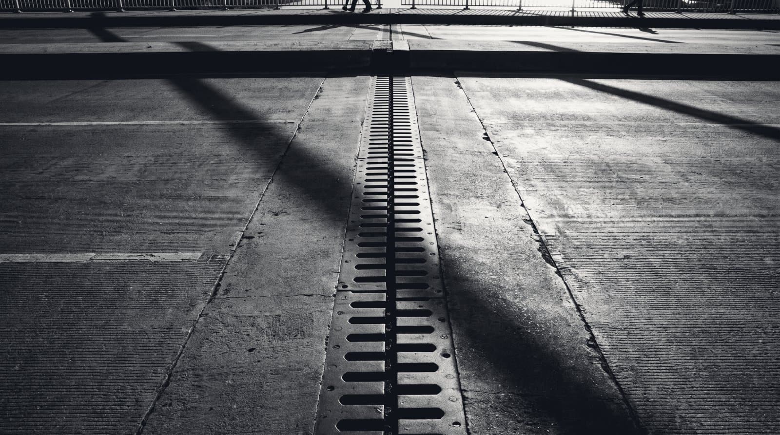 The expansion joint between two concrete bridge deck slabs, a dark gap and steel finger plates running across the frame.