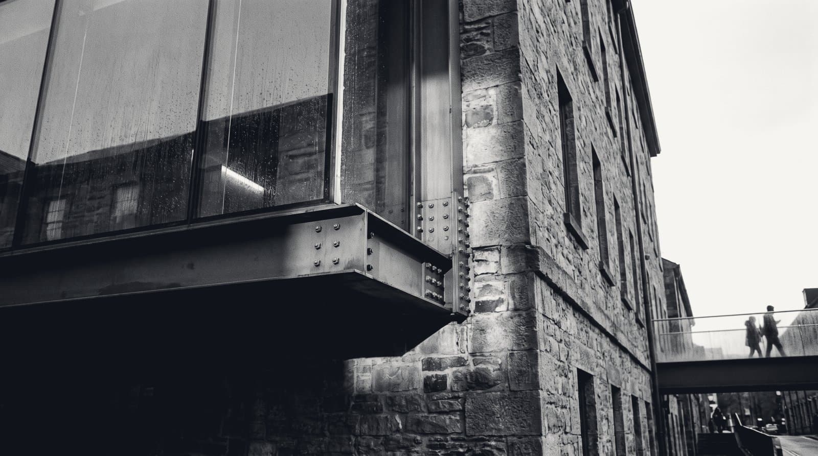 A glass and steel extension grafted onto an older masonry building, the seam between the two visible.