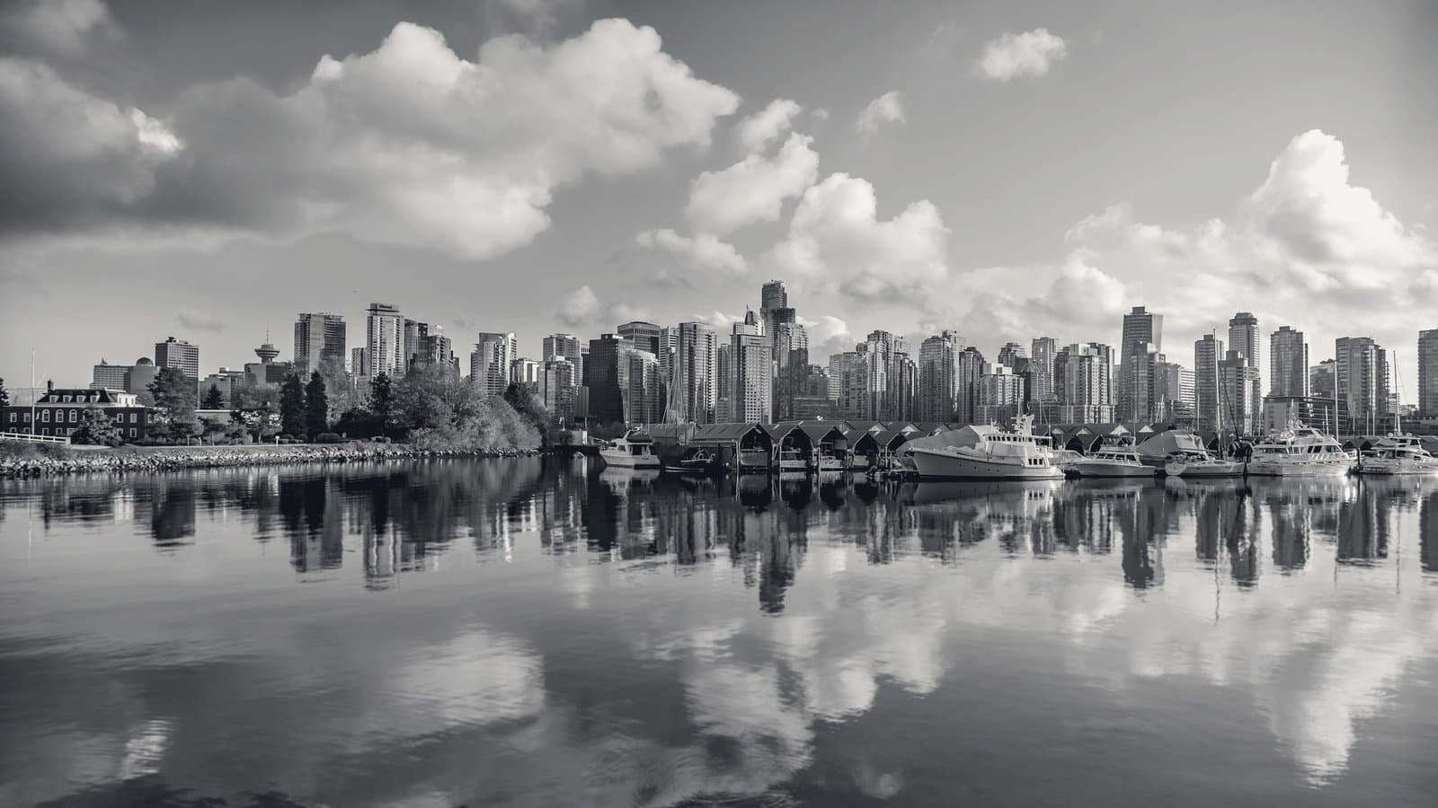 A skyline and its reflection across a calm harbor.