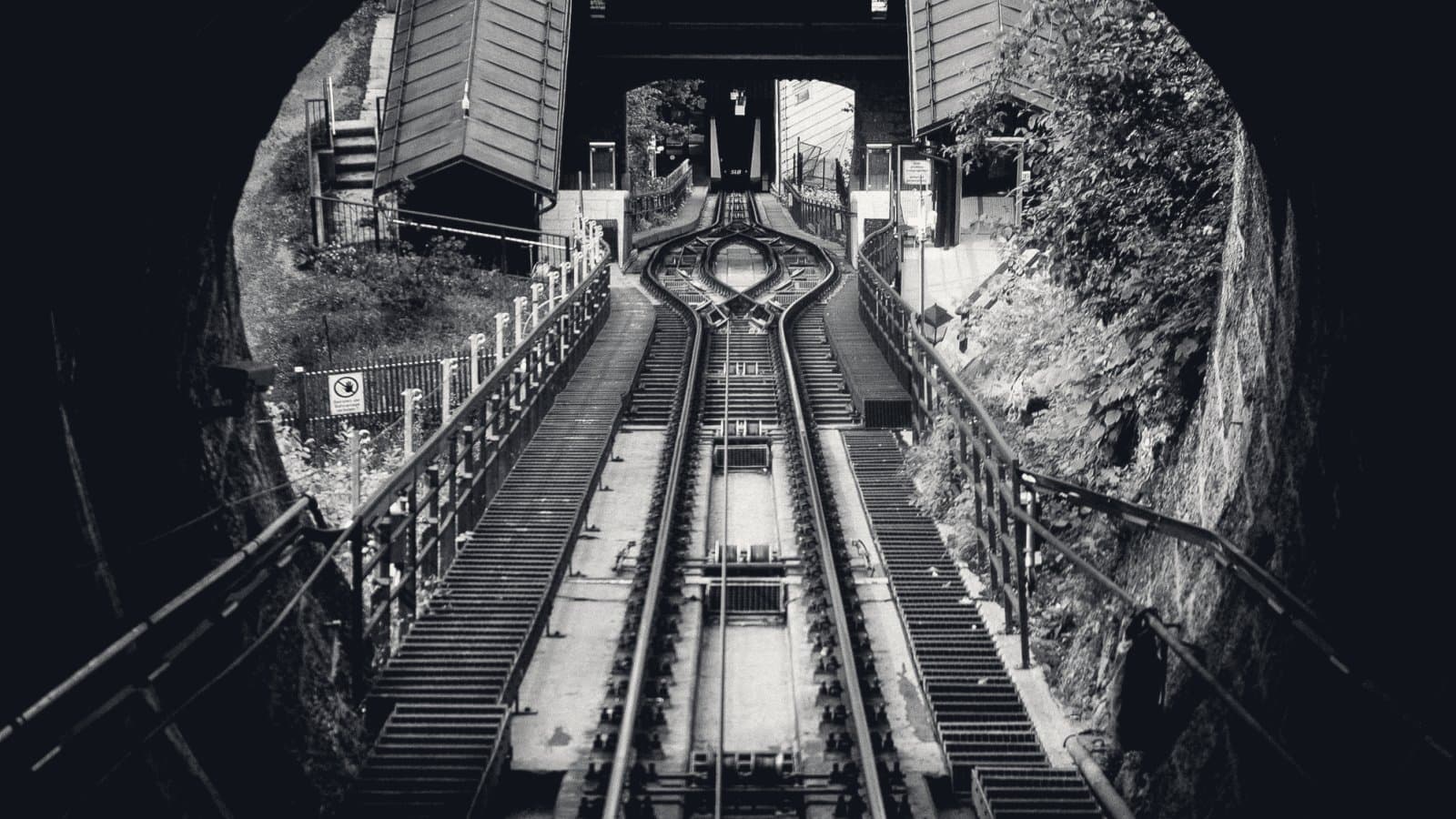 A steep funicular railway seen from the mouth of a tunnel, the single track splitting into a passing loop halfway up the incline and rejoining below the upper station.