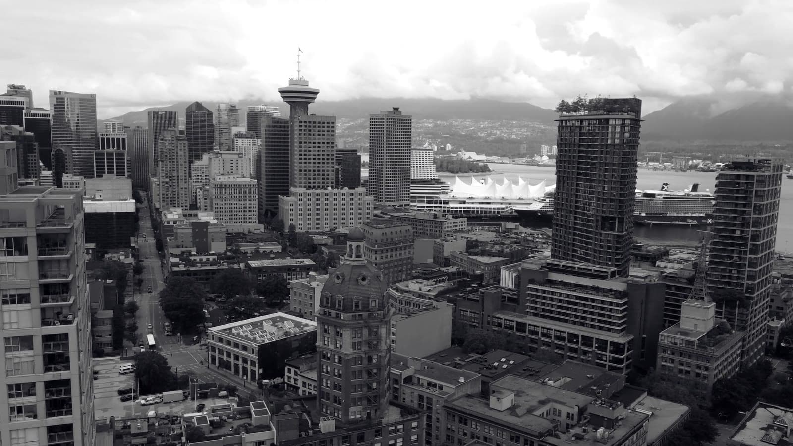 The Canada Place inlet under low cloud, a ship passing the gateway.