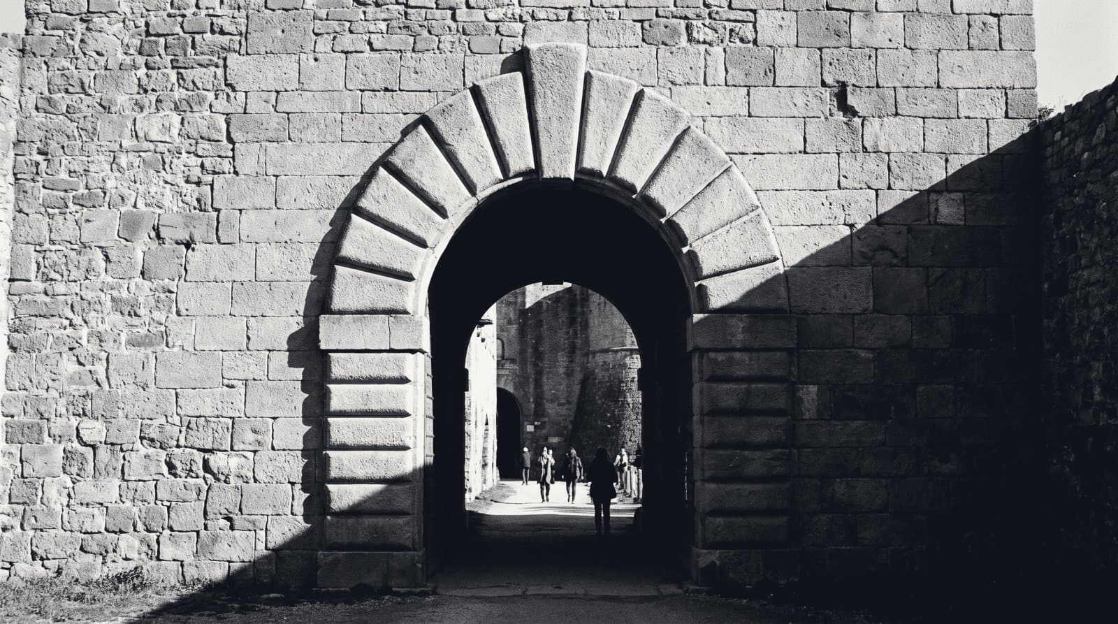 A single heavy stone arch with a pronounced keystone in a thick masonry wall.