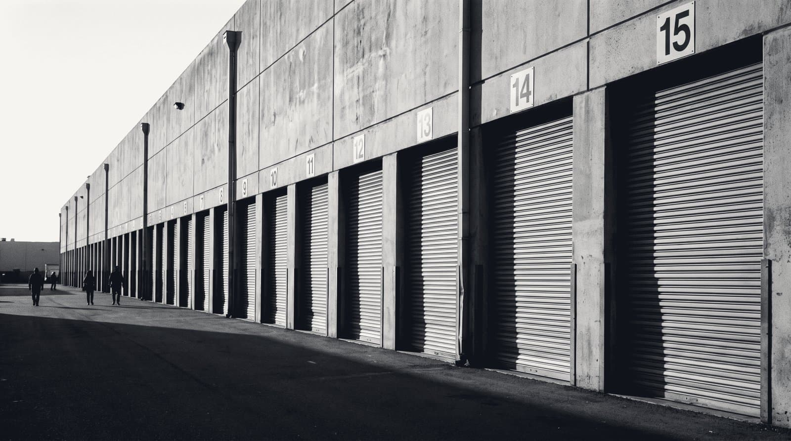 A long row of numbered roller-shutter loading dock doors along a distribution warehouse wall.