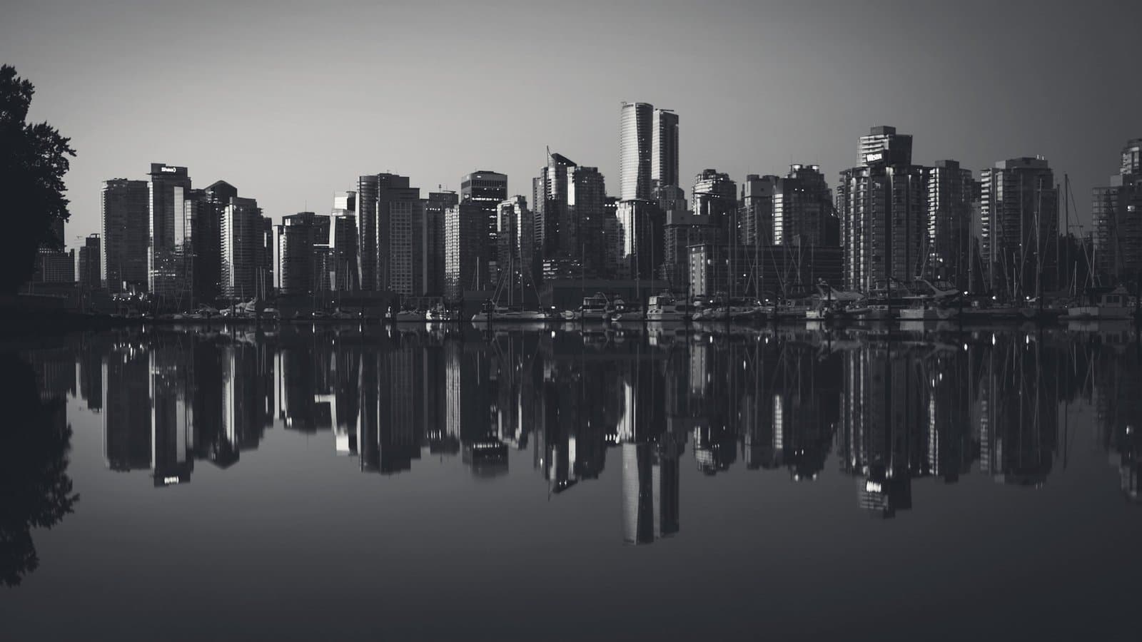 A city skyline mirrored in still water at dusk.