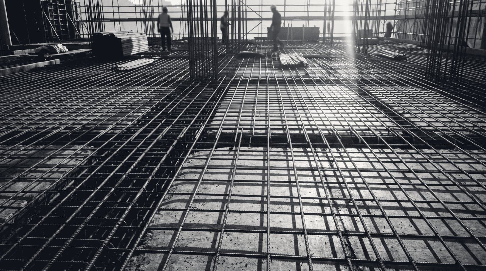 A dense grid of steel reinforcing bar tied over a poured concrete deck on a construction site.