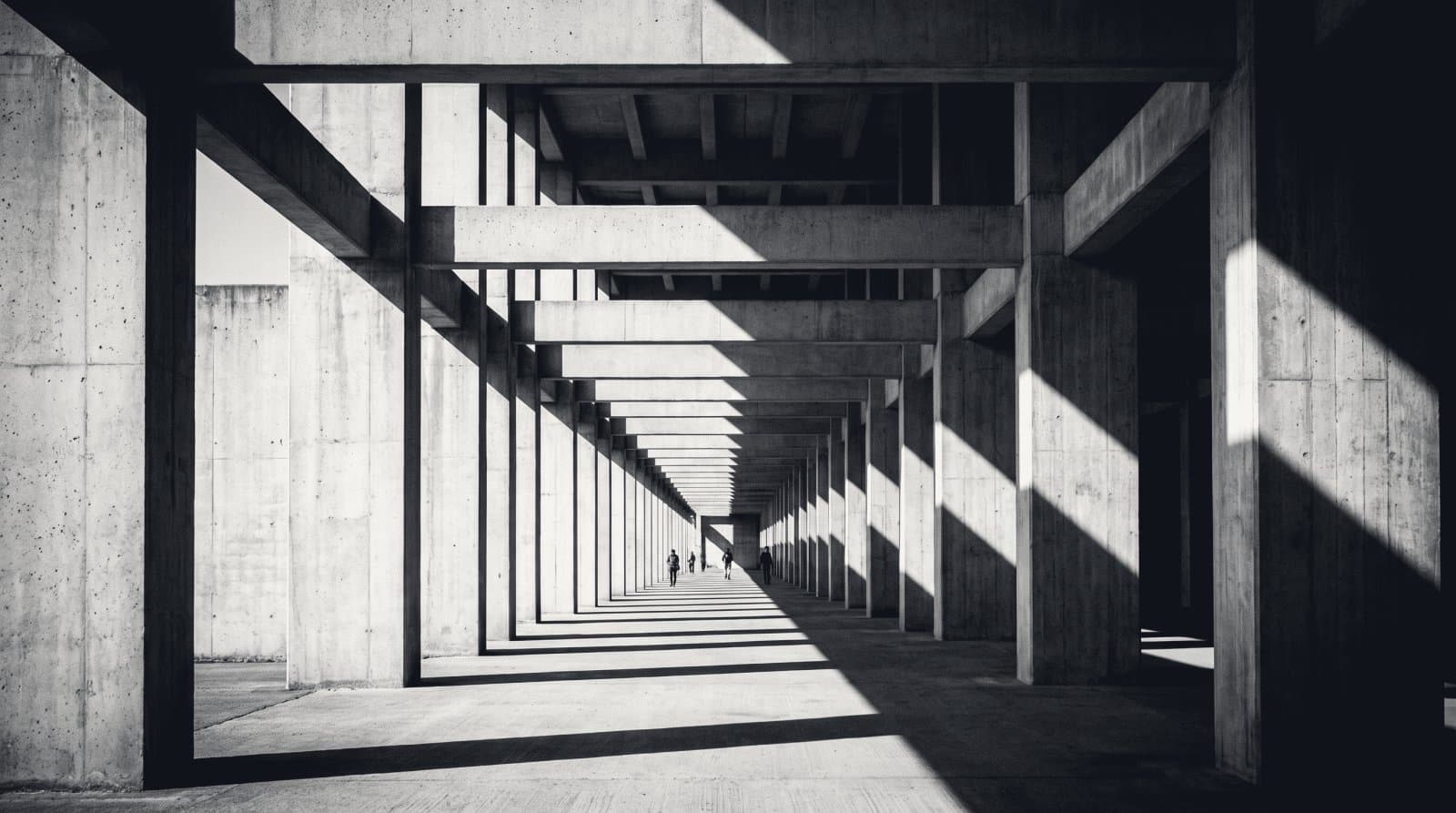 The repeating structural bays of a concrete warehouse colonnade seen down its length.