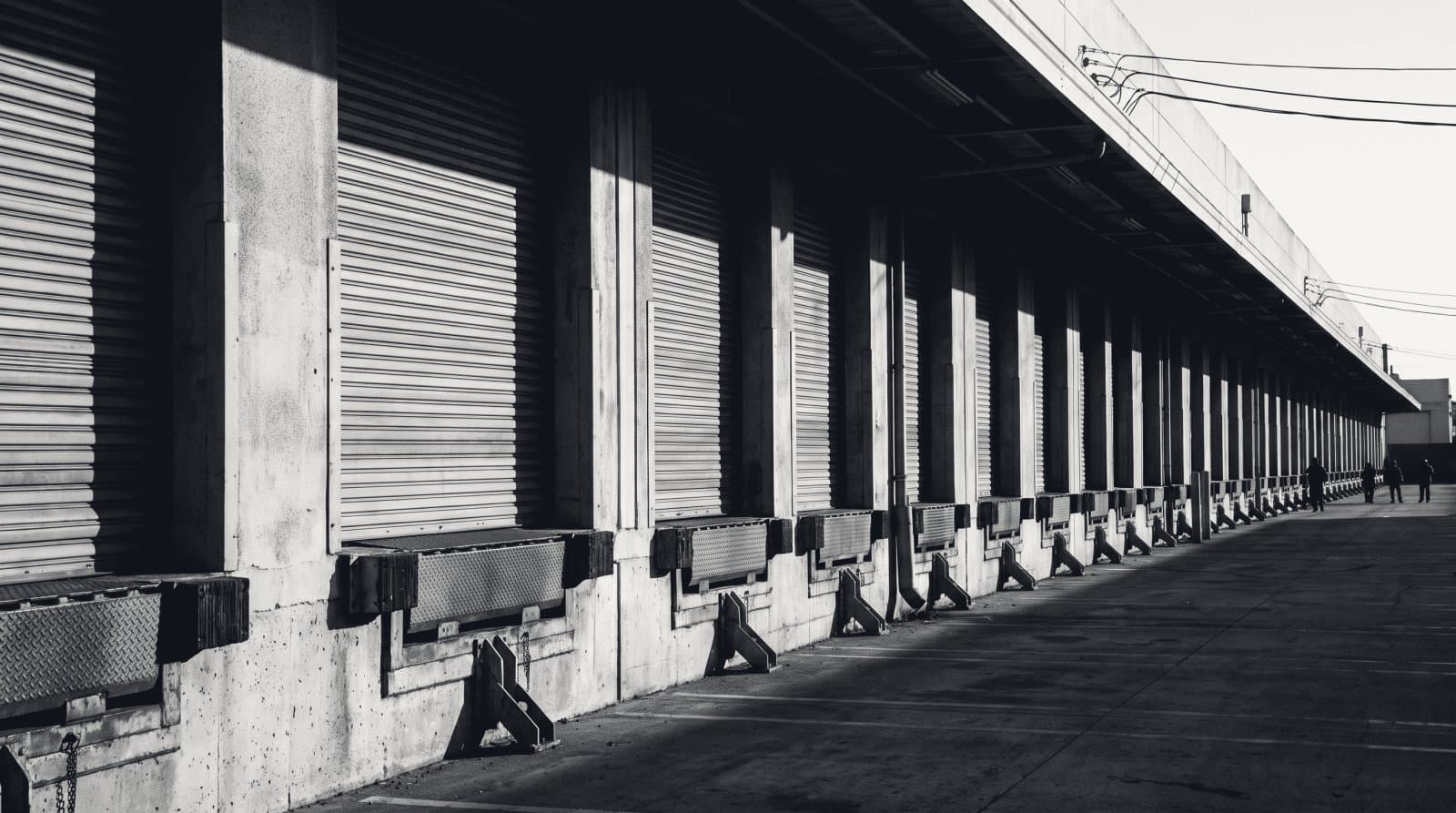 A long warehouse loading dock with a receding row of roller shutter doors and levellers.
