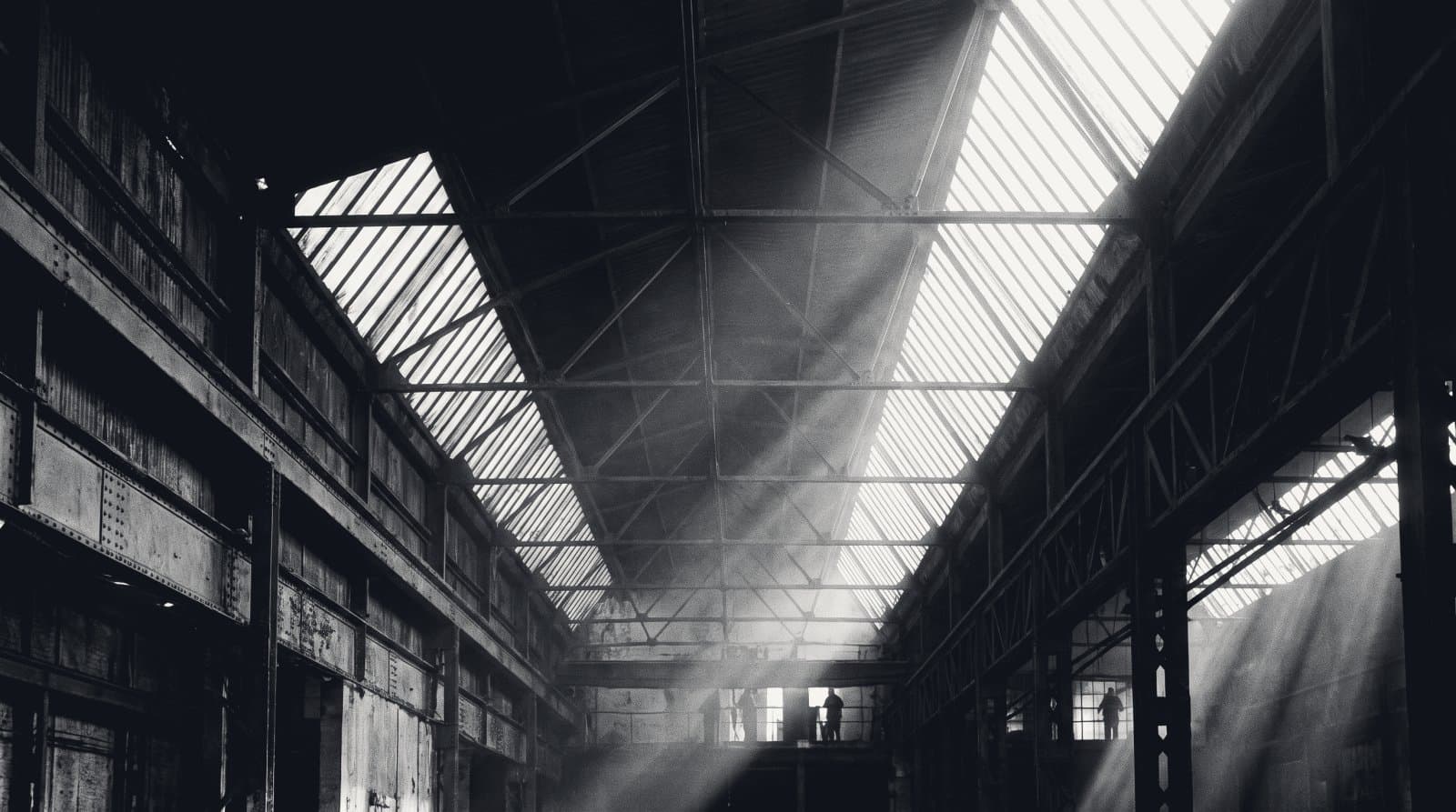 The sawtooth north-light roof of an old factory shed seen from inside.